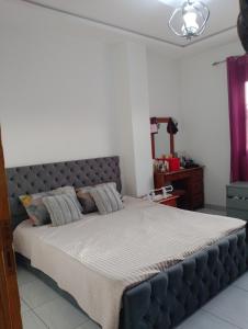 a bedroom with a large bed with a gray headboard at Résidence in Matriouene
