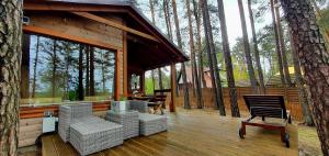 a screened in porch of a cabin with chairs and a tree at Domki LeMo - nad samym jeziorem, nowe w pełni wyposażone z miejscem parkingowym in Borsk