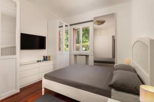 una camera da letto bianca con un letto e una TV a schermo piatto di The Garden's Home-Casa Rimini Marina centro a Rimini