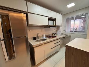 uma cozinha com uma geladeira de aço inoxidável e uma pia em LUX26 - Flat Próx Órion Cozinha Completa com Varanda em Goiânia