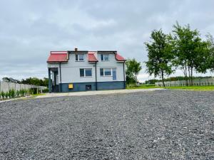 a white house with a red roof on a gravel road at Noclegi Rychwał in Rychwał