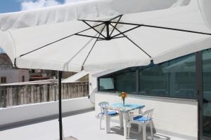 a table and chairs under a white umbrella on a balcony at Casa Marietta in Lipari