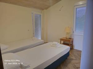a white bedroom with two beds and a table at Hotel Albani in Lezhë