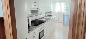 a white kitchen with a sink and a microwave at Apartamento Aiguablava Playa de Gandía in Playa de Gandia