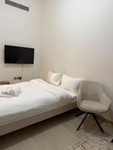 Un dormitorio con una cama y una silla y un televisor. en EGATE - Studio - 10th Floor - Balcony with a View - 01-1014, en Dubái