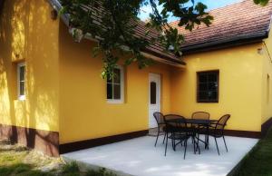 a patio with chairs and a yellow house at Gólyaház in Réde