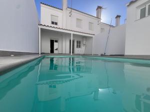 una piscina di fronte a un edificio bianco di Casa Rural Castillo de Alanis ad Alanís