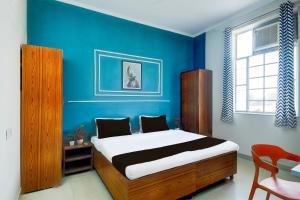 een slaapkamer met een bed met een blauwe muur bij Hotel O SS in Jaipur +21 foto's