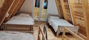 two twin beds in a room with wooden floors at Planinski san in Žabljak