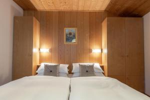 a bedroom with two beds and wooden walls at Villa Resi Apartments in Corvara in Badia