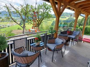 a porch with chairs and tables and a view of the mountains at Weitblick Hof in Sankt Paul im Lavanttal