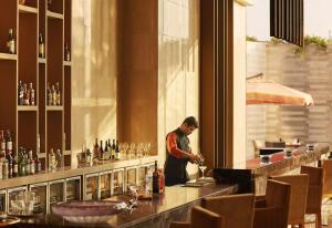 a man standing at a bar in a restaurant at Taj Bangalore in Devanahalli-Bangalore