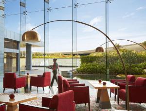 a restaurant with red chairs and tables and a large window at Taj Bangalore in Devanahalli-Bangalore