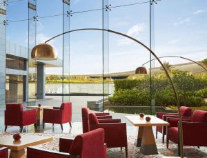 a restaurant with red chairs and tables and a large window at Taj Bangalore in Devanahalli-Bangalore