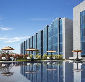 a building with chairs and umbrellas and a pool at Taj Bangalore in Devanahalli-Bangalore