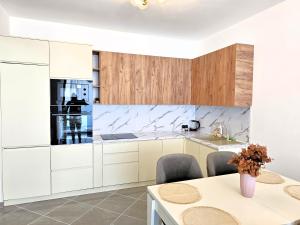 a kitchen with white cabinets and a table with chairs at Sunset Luxury Apartment in Vlorë