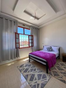 a bedroom with a purple bed and a window at Residence Dallas Warzazate in Ouarzazate