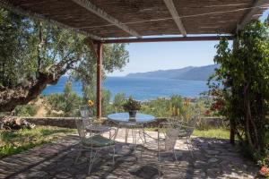 a table and chairs on a patio with a view of the ocean at Rosso Antico Tower by ΜΡS in Kotronas