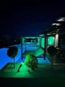 a house lit up at night with green lights at STELIA Villa Halkidiki in Kallithea Halkidikis