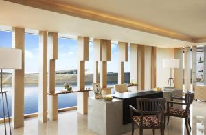 a living room with large windows and a table and chairs at Taj Bangalore in Devanahalli-Bangalore