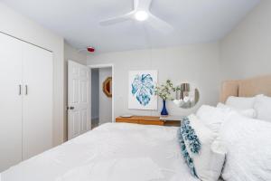 une chambre blanche avec un grand lit et un ventilateur de plafond dans l'établissement Oceanfront Condo Kailua Kona Walk to Beach Town and Sunset Views, à Kailua-Kona