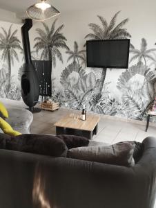 ein Wohnzimmer mit Couch und Flachbildfernseher in der Unterkunft La Brocéliande enchantée in Iffendic