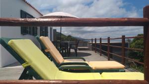 a balcony with chairs and an umbrella and a table at Casa da Baixa da Ribeirinha in Baixa