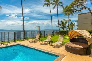 a backyard with a swimming pool and chairs and a grill at Lauloa 407 by Coldwell Banker Island Vacations in Wailuku