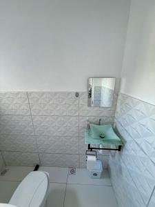 a bathroom with a toilet and a green sink at Microcasa 2 - Centro Maricá in Maricá