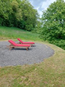 a picnic table with two red benches on a gravel road at Weitblick Hof Tiny House in Sankt Paul im Lavanttal