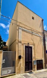 a brown building with a door and a gate at Via Cufra 46 in Botrugno