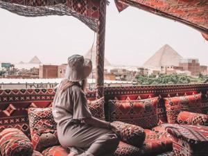 カイロにあるmajestic hotel pyramids viewのソファに座ってピラミッドを眺める女性