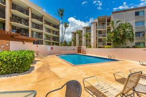 a swimming pool in the middle of a courtyard with chairs at Milowai 101 by Coldwell Banker Island Vacations in Wailuku