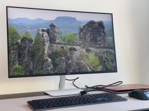 a computer monitor with a keyboard and mouse on a desk at Fernblick - Ferienwohnung mit Bastei-Aussicht in Kurort Rathen