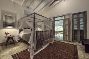 a bedroom with a canopy bed and a living room at Taru Villas Mawella - Tangalle in Tangalle