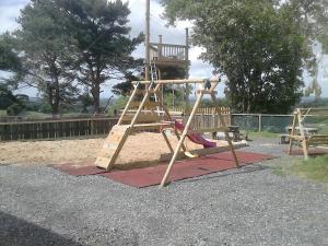 um parque infantil com uma estrutura de jogos de madeira na areia em Green Adventure EcoHostel em Clonmore