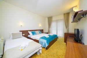 a hotel room with two beds and a flat screen tv at Hotel Odissey Jaz in Budva