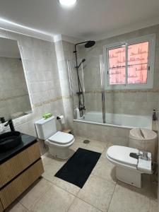 a bathroom with two toilets and a sink and a tub at Royal Palace- Granada Park in Arona