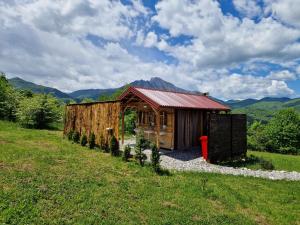 a small wooden cabin with a red roof in a field at Mountain Camp Outdoor Tara in Tjentište