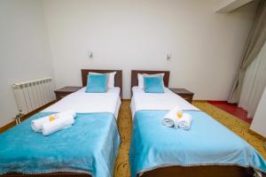 two beds in a room with blue and white sheets at Hotel Odissey Jaz in Budva