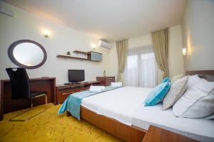 a bedroom with a bed and a desk and a mirror at Hotel Odissey Jaz in Budva +24 photos