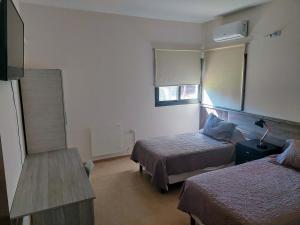 a hotel room with two beds and a table at Altos del TALAMPAYA in Villa Unión +25 photos