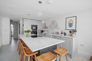 a kitchen with a white counter top and wooden chairs at Bay View Luxury Stays - Iris Harbour Cottage in Rodwell +13 photos