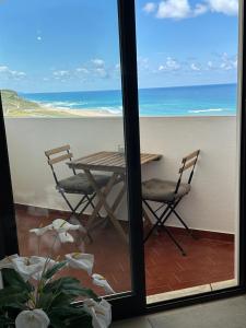 a table and chairs on a balcony with a view of the ocean at Face a l'océan - Praia da areia branca, vue mer in Praia da Areia Branca