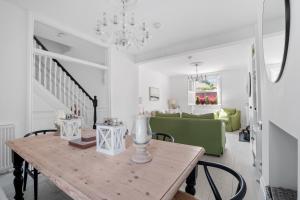a dining room with a table and a green couch at Bay View Luxury Stays - Iris Harbour Cottage in Rodwell