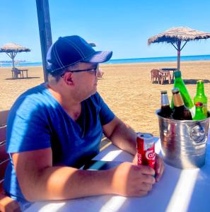 a man sitting at a table with bottles of beer at Buzovna Delmar Luxury Residence in Baku