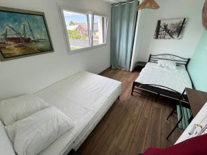 Una sala de estar con dos camas y una ventana. en Les maisons Inael, en Pénestin