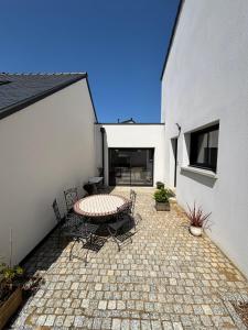 Un patio con una mesa y sillas al lado de un edificio. en Les maisons Inael, en Pénestin