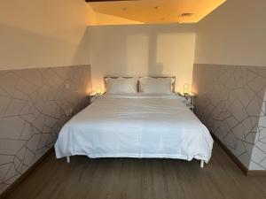 a bedroom with a large white bed with two lamps at Cozy Studio Apartment in Dubai