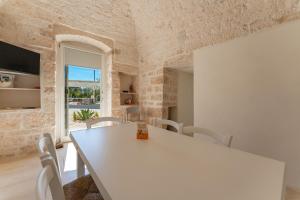 a white dining room with a white table and chairs at Trulli DaMì in Ceglie Messapica